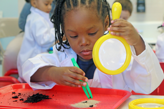 little girl holding an object with tweezers 